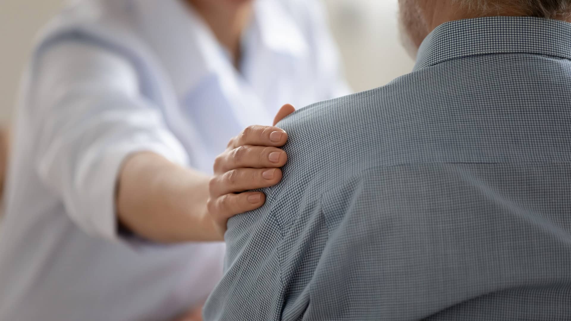 Caring doctor comforting old patient